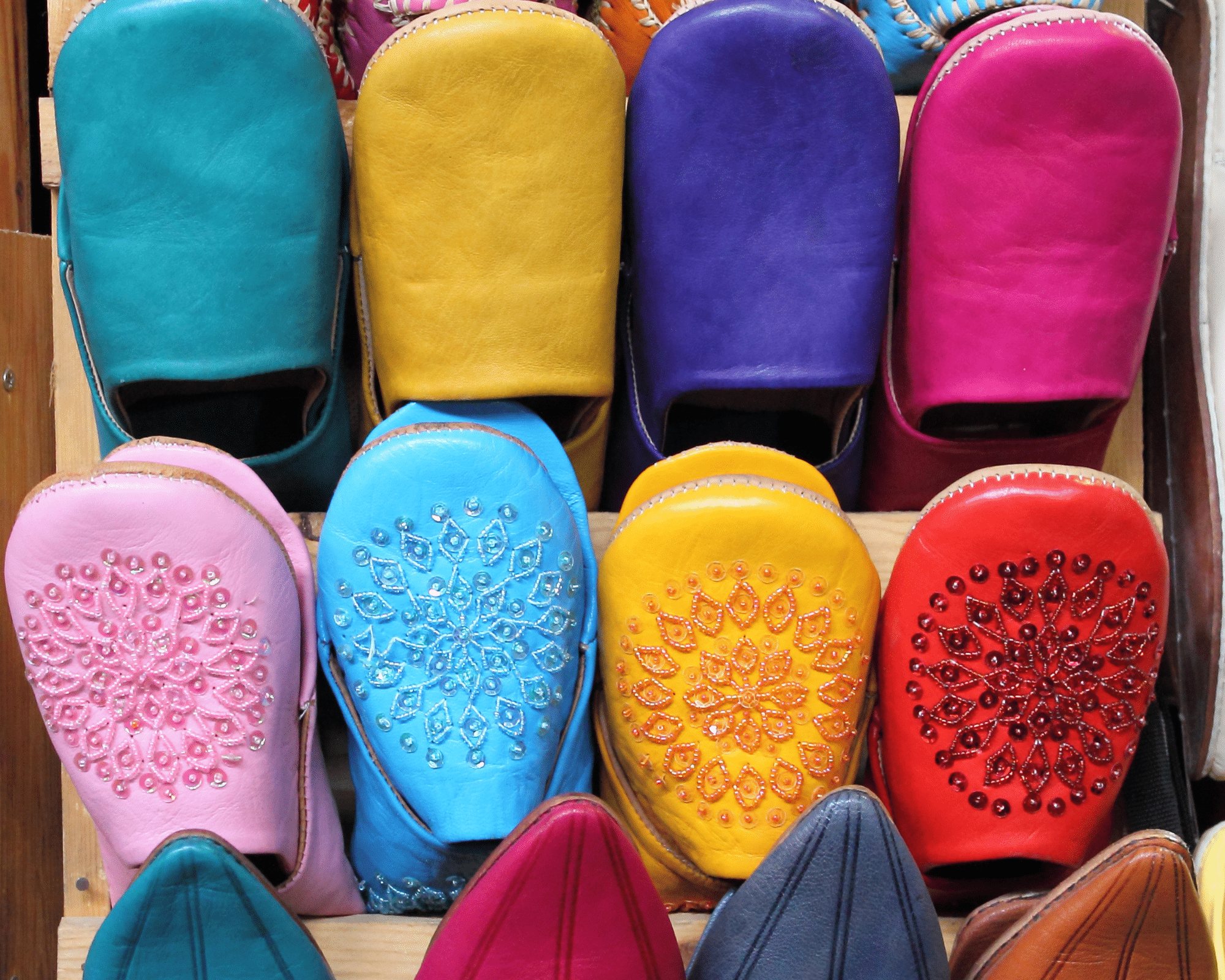 chaussons en cuir de différentes couleurs présenté sur un meuble en bois