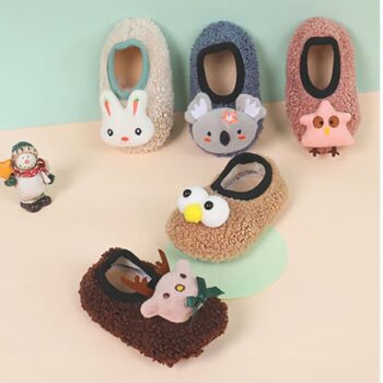 Plusieurs chaussons de la même gamme , avec des petites têtes d'animaux sur le dessus, sont appuyés contre le mur, et deux autres sont au sol