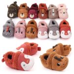 Plusieurs paires de chaussons pour bébé avec visage de petits animaux dessus, ils sont disposés, les uns à côté des autres sur fond blanc et deux paires sont mises en avant , une rouge et une marron