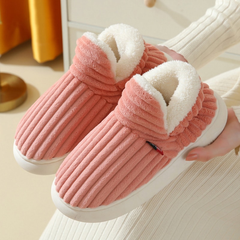 Une paire de bottes chaussons roses qui sont montrées et tendues par deux mains.
