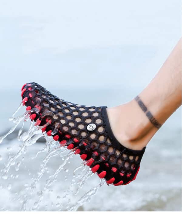 chausson d'eau que l'on voit porté sur un pied, rouge et noir, à trou et qui vient de sortir de l'eau,