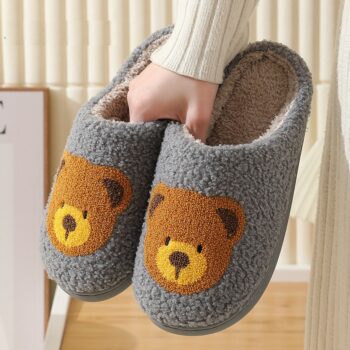 Chausson tricot en coton gris avec logo ours mingon marron pour femmes, avec la main d'une personne qui tient la paire de chausson dans sa main