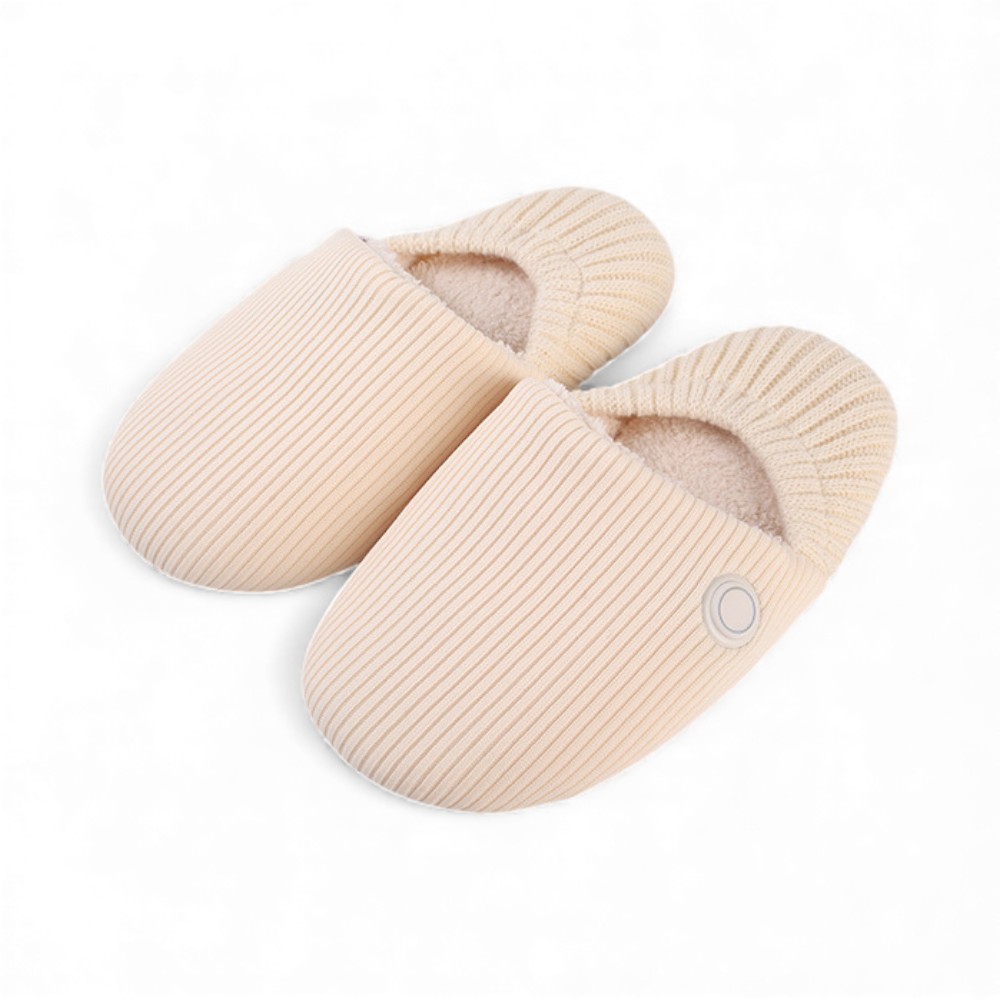 Paire de chaussons chauffants rechargeables sans fil beige pour femme avec un bouton latéral qui permet de régler l'intensité de la chaleur, sur fond blanc uni.